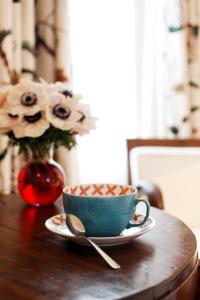 une tasse et une cuillère sur une table avec un vase et des fleurs dans l'établissement Hotel La Manufacture, à Paris