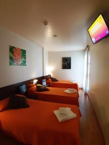 a hotel room with two beds and a television at Hostal Nirvana in Ponferrada