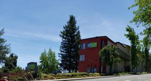 a red building with a tree next to a street at SureStay Hotel by Best Western Vallejo Napa Valley in Vallejo