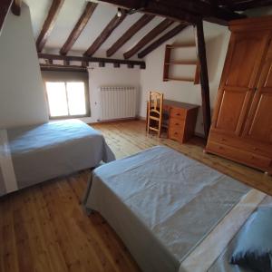 a bedroom with two beds and a dresser and a window at La Casa del Rastro in El Burgo de Osma