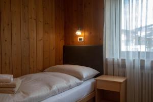 Una cama sentada en una habitación con ventana. en Apartments Ciasa Colz, en La Villa