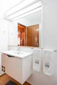 uma casa de banho com um lavatório branco e um espelho. em Carcavelos Beach & Business by The Portuguese Butler em Carcavelos