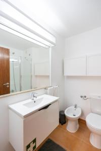 uma casa de banho branca com um lavatório e um WC em Carcavelos Beach & Business by The Portuguese Butler em Carcavelos