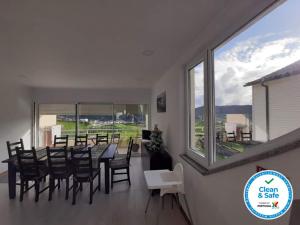 una sala da pranzo con tavolo, sedie e una grande finestra di The Furnas Azores House a Furnas