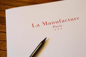 un morceau de papier avec un stylo au dessus de celui-ci dans l'établissement Hotel La Manufacture, à Paris