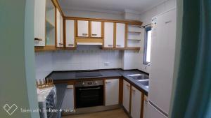een kleine keuken met houten kasten en een wastafel bij Precioso apartamento 3hab en Valencia (Benimaclet) in Valencia