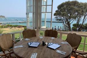 a wooden table with chairs and a view of the ocean at Sorrento Back Beach Apartment at Oceanic Apt 7 in Sorrento