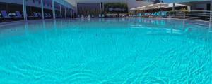 une grande piscine d'eau bleue dans un bâtiment dans l'établissement Hotel Pantelidis, à Ptolemaïda