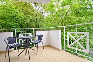 a balcony with two chairs and a table and trees at CRYSTAL Apartament 80m od plaży in Kołobrzeg