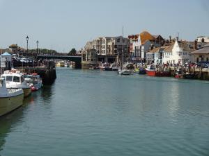 une rivière avec des bateaux amarrés dans une ville avec un pont dans l'établissement Freshford House, à Weymouth 5 autres photos