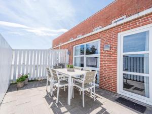 eine Terrasse mit einem weißen Tisch und Stühlen sowie einem Backsteingebäude in der Unterkunft Modern Beach Retreat in Blavand-By Traum in Blåvand