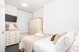 um quarto branco com uma cama e uma cómoda em Velvet Coaster Apartments em Blackpool