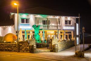 ein Gebäude mit einem grünen Objekt in der Nacht davor in der Unterkunft Hotel Restaurant Artemis in Weisenheim am Berg