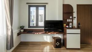 Una habitación con un escritorio con televisión y una ventana. en Heaven Villa Hotel Nha Trang, en Cam Ranh