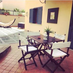 a wooden table with white chairs and a table and a hammock at Dino's B&B in Casapulla
