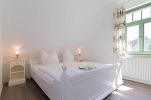 a white bed in a white bedroom with a window at Ferienhaussiedlung Strandperlen Sanddornhof 3c (Typ II) in Wustrow