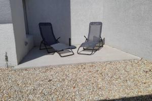 two chairs are sitting next to a building at Maison Aigues-Mortes 8 couchages in Aigues-Mortes