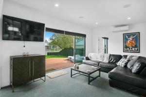 a living room with a couch and a tv at Sky Above Beach Below - Waihi Beach Holiday Home in Waihi Beach