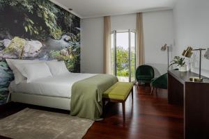 a bedroom with a bed with a painting on the wall at Senhora da Rosa, Tradition & Nature Hotel in Ponta Delgada