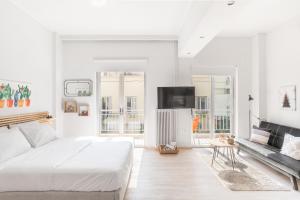 biała sypialnia z dużym łóżkiem i kanapą w obiekcie Koukaki Studio with a Sunny Balcony, near the Acropolis w Atenach