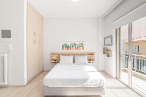 biała sypialnia z dużym łóżkiem i dużymi oknami w obiekcie Koukaki Studio with a Sunny Balcony, near the Acropolis w Atenach
