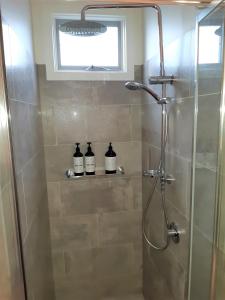 una ducha con 3 botellas en un estante del baño en Port Central No 4, en Port Campbell