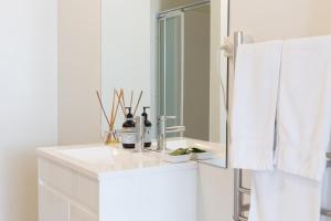 a white bathroom with a sink and a mirror at Highbury Apartments in Launceston