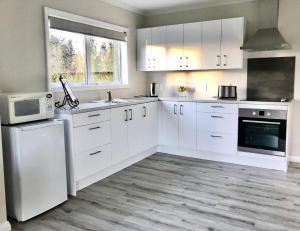 a white kitchen with white cabinets and a microwave at Maungatautari Outlook Cambridge in Cambridge