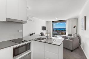 a kitchen with a sink and a living room at Landmark Resort in Nelson Bay