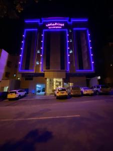 a lit up building with cars parked in a parking lot at بيت الماس للشقق الفندقية MAAS House Apartments in Abha