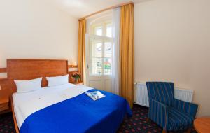 um quarto com uma cama azul e uma cadeira azul em Hotel & Apartments Zarenhof Berlin Prenzlauer Berg em Berlim