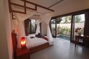 ein Schlafzimmer mit einem Himmelbett und einem Pool in der Unterkunft Ratna Villa in Ubud