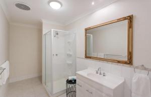 
a bathroom with a tub, toilet, sink and mirror at Siroque Fremantle in Fremantle
