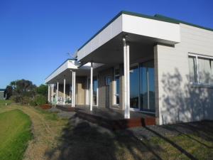 a white building with windows and a yard at Room with a view in Waipu