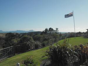 a flag on a hill with a green field at Room with a view in Waipu
