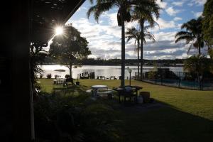 a view of a lake with palm trees and tables at Lake Edge Apartments in Burrill Lake