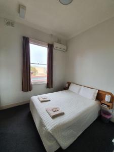 a bedroom with a bed with two towels on it at Empire Hotel Goulburn in Goulburn