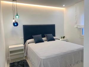 een witte slaapkamer met een groot bed met een blauw hoofdeinde bij Apartamento Playas del Duque - Puerto Banús - Marbella in Marbella