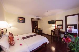 a hotel room with two beds and a desk at Smiling Hotel in Siem Reap