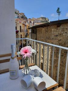 a table with a bottle of wine and flowers on a balcony at Scilla's Dream in Scilla
