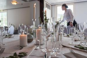 una mesa con velas y copas de vino y una mujer en Dølen Hotel, en Evje