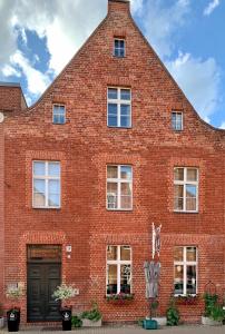 - un bâtiment en briques rouges avec une porte et des fenêtres noires dans l'établissement Apartmenthaus im holländischen Viertel, à Potsdam