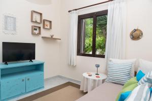 a living room with a blue cabinet and a tv at ILIOCHARI sea view apartments Oropos - Kalamos in Kalamos