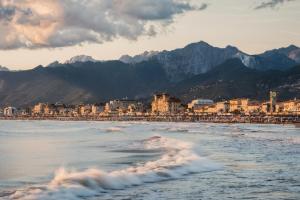 a beach with a town and mountains in the background at Il Sole Antico in Viareggio