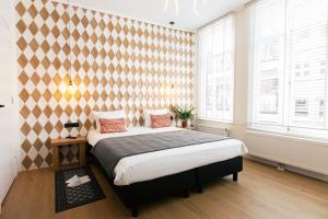 ein Schlafzimmer mit einem großen Bett in einem Zimmer mit Fenstern in der Unterkunft Quentin Golden Bear Hotel in Amsterdam