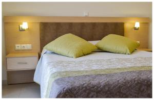 a bedroom with a large bed with two yellow pillows at Potideon Bay Luxury Apartments in Karpathos Town