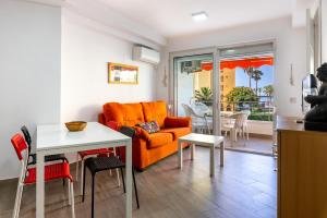 a living room with an orange couch and a table at Apartamento primera linea playa Algarrobo Costa in Algarrobo-Costa