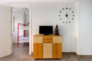 a living room with a television on a wooden cabinet at Apartamento primera linea playa Algarrobo Costa in Algarrobo-Costa
