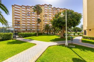 a large apartment building with a park in front of it at Apartamento primera linea playa Algarrobo Costa in Algarrobo-Costa