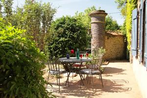 a table and chairs in a garden with a brick pillar at le clos des artistes - Gîte in Turny